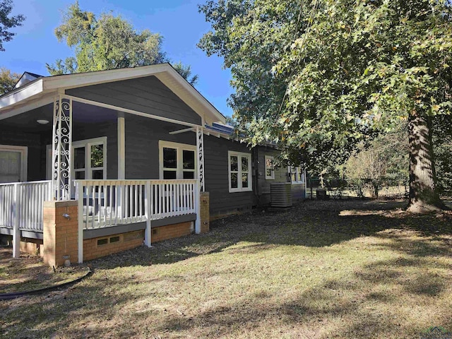 view of side of property with covered porch, a yard, and central AC