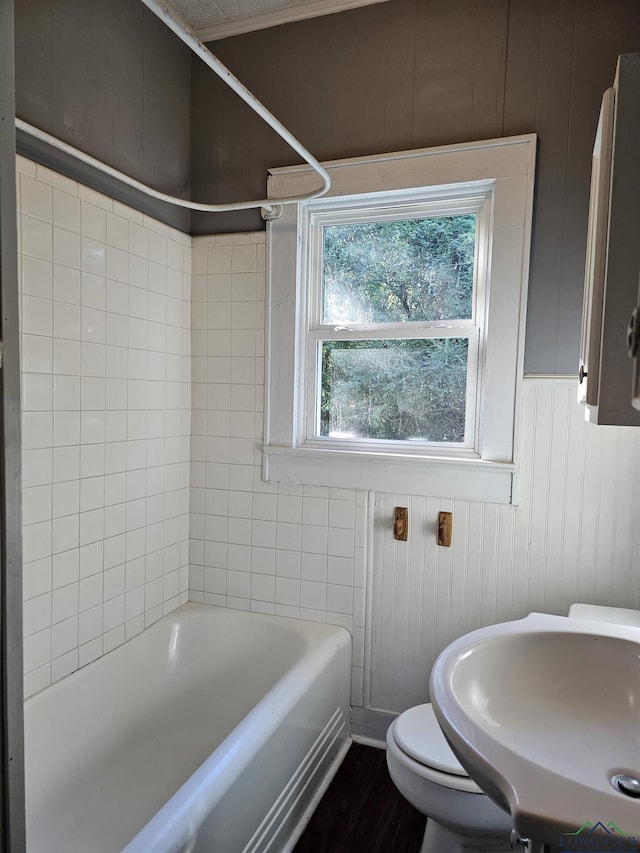 bathroom with hardwood / wood-style flooring, wood walls, toilet, and sink