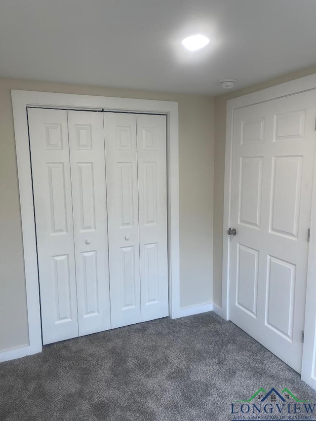 unfurnished bedroom featuring a closet and dark colored carpet