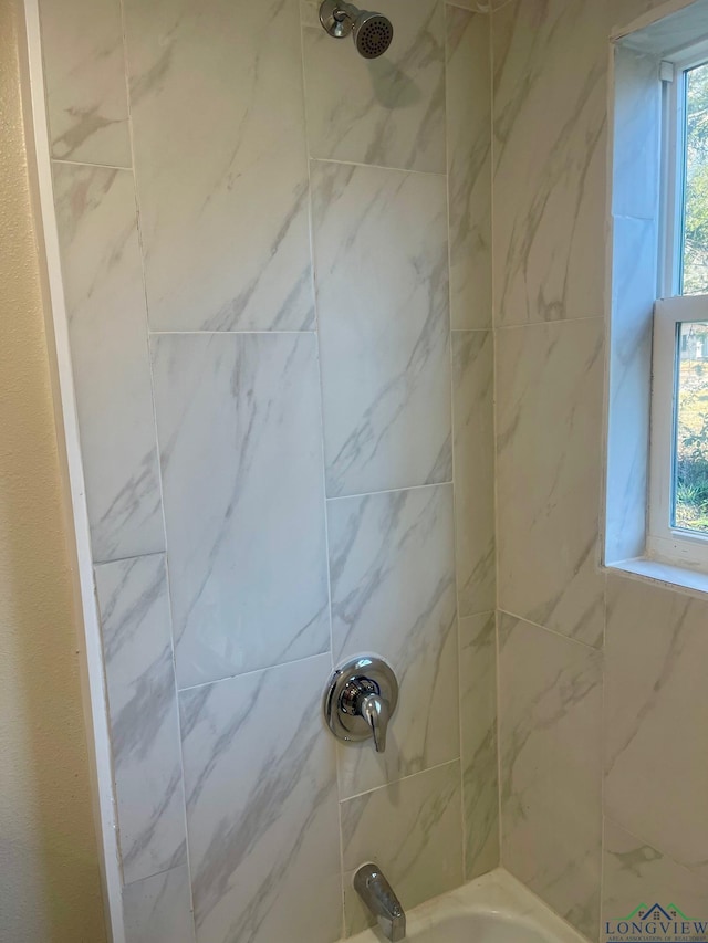 bathroom featuring a healthy amount of sunlight and tiled shower / bath combo