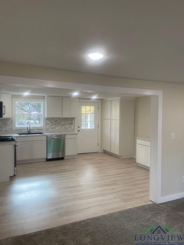 kitchen with white cabinetry, dishwasher, plenty of natural light, and sink