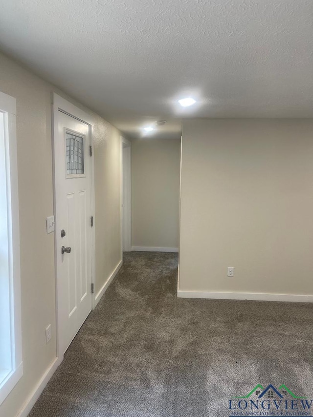 empty room with dark carpet and a textured ceiling