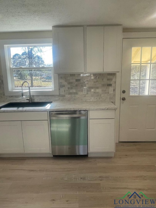 kitchen with white cabinetry, sink, decorative backsplash, stainless steel dishwasher, and light hardwood / wood-style floors