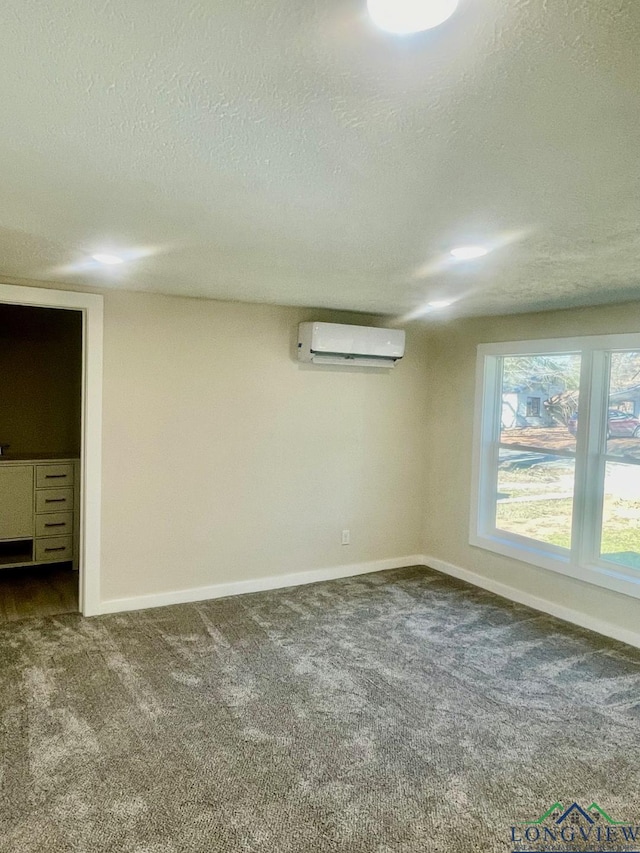 basement with an AC wall unit, carpet floors, and a textured ceiling