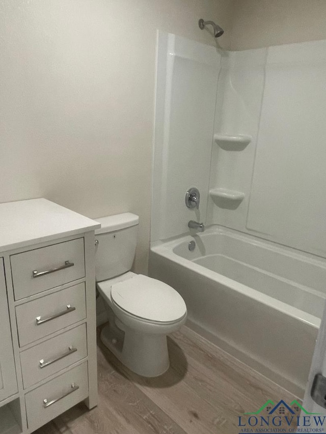 bathroom featuring hardwood / wood-style flooring, shower / washtub combination, and toilet