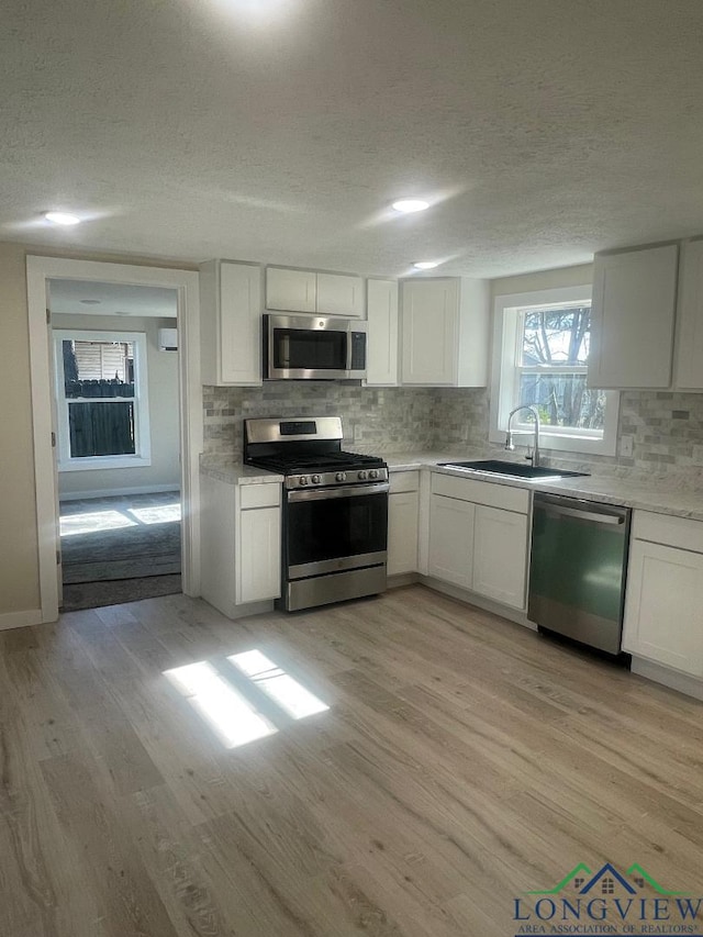 kitchen with white cabinetry, light hardwood / wood-style flooring, and appliances with stainless steel finishes