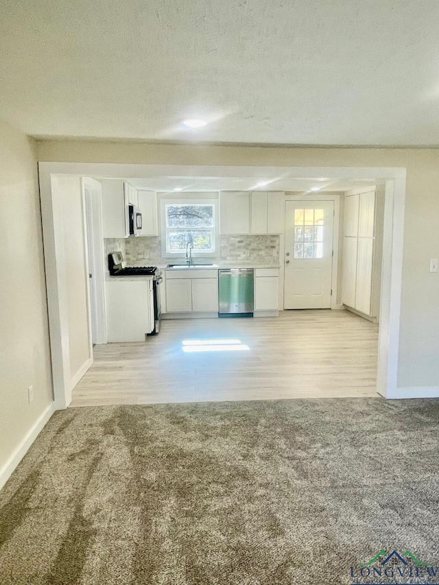 kitchen with white cabinetry, sink, stainless steel appliances, and light hardwood / wood-style floors