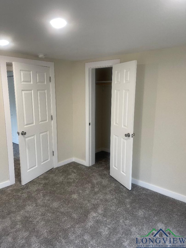 unfurnished bedroom with a closet and dark colored carpet