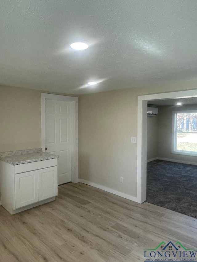 empty room featuring a wall unit AC, a textured ceiling, and light hardwood / wood-style floors