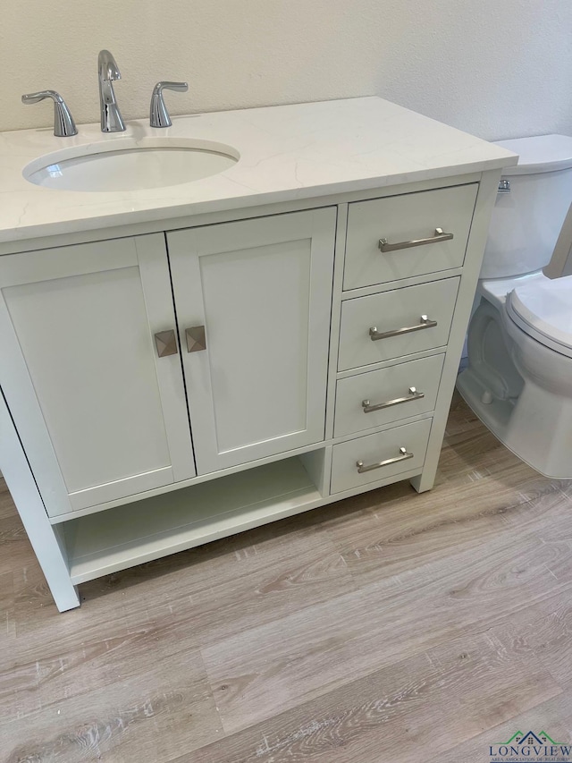 bathroom with vanity, toilet, and hardwood / wood-style floors