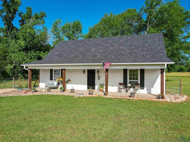 view of front facade featuring fence, a shingled roof, covered porch, and a front yard