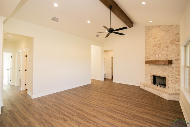 unfurnished living room featuring a fireplace, beam ceiling, dark hardwood / wood-style floors, and high vaulted ceiling