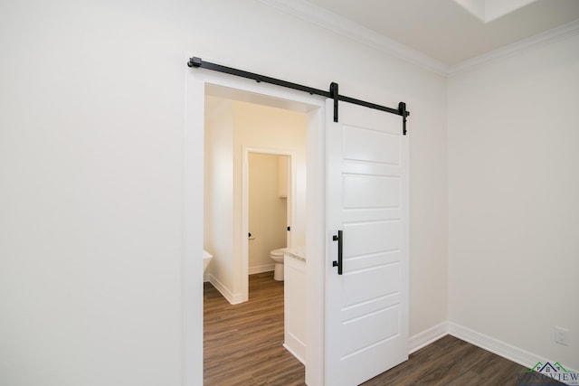 hall with dark hardwood / wood-style floors, a barn door, and ornamental molding