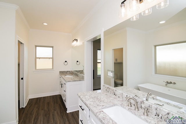 bathroom featuring ornamental molding, vanity, a bath, wood-type flooring, and toilet