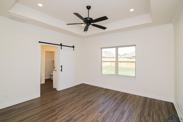 unfurnished room with a tray ceiling, a barn door, ceiling fan, and dark hardwood / wood-style flooring