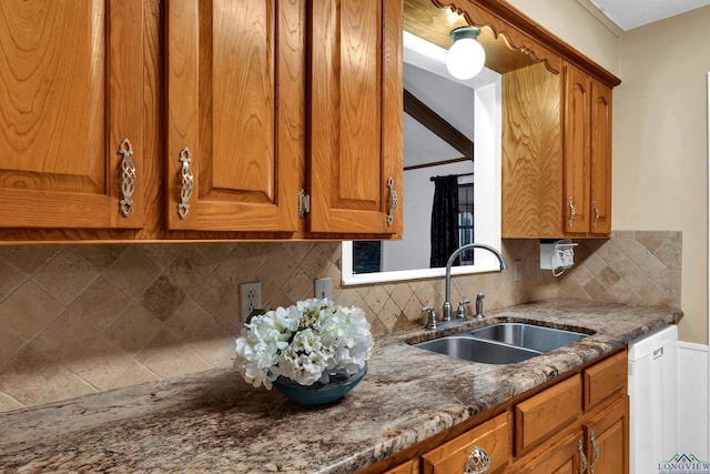 kitchen featuring dishwasher, dark stone countertops, sink, and tasteful backsplash