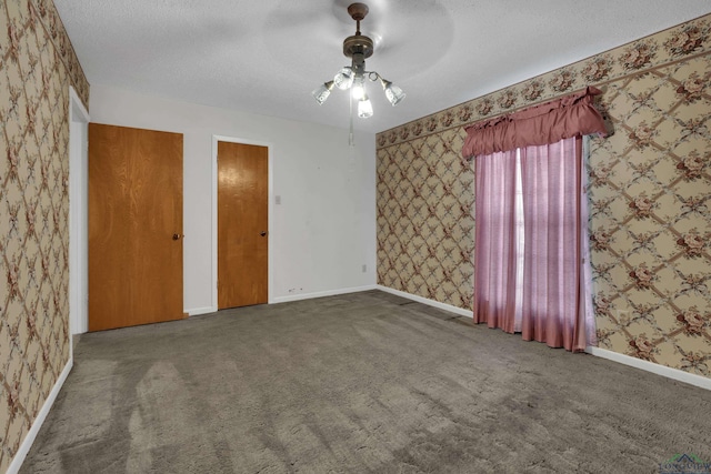 unfurnished bedroom with dark colored carpet, a textured ceiling, and ceiling fan