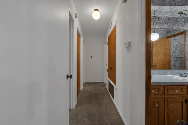 hall featuring carpet flooring, sink, and a textured ceiling