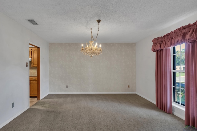 unfurnished room featuring light carpet, a textured ceiling, and an inviting chandelier