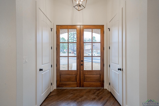 doorway featuring an inviting chandelier, dark wood-type flooring, and french doors