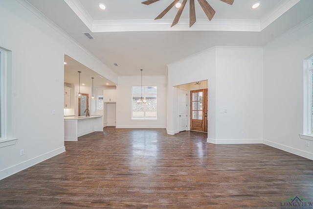 unfurnished living room with dark hardwood / wood-style floors, a tray ceiling, and crown molding