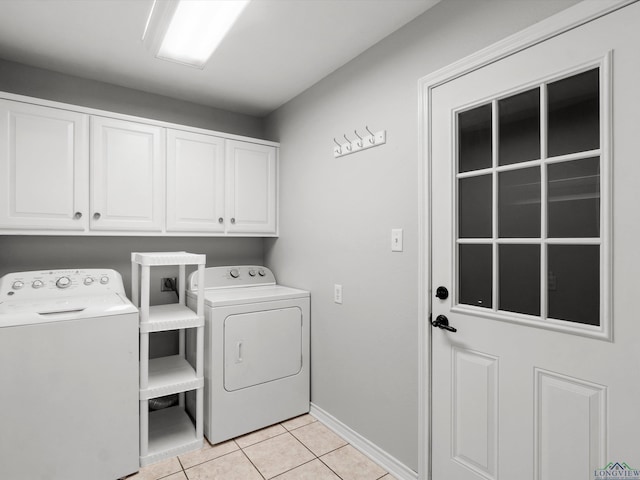 washroom featuring cabinet space, light tile patterned flooring, washing machine and clothes dryer, and baseboards