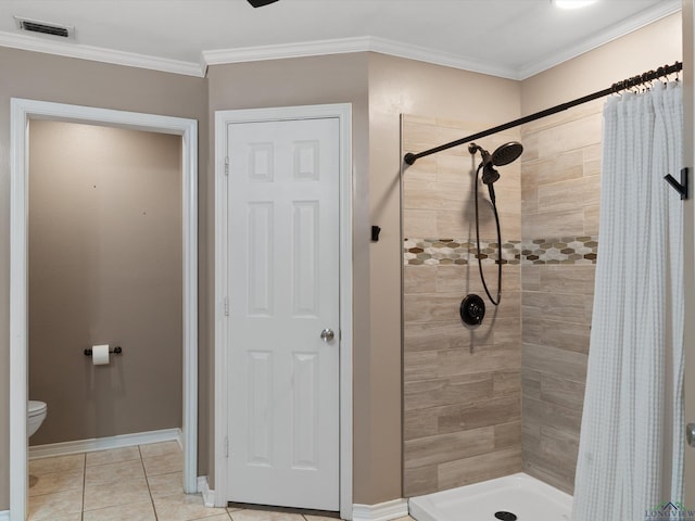 full bath with a shower stall, toilet, tile patterned floors, baseboards, and crown molding
