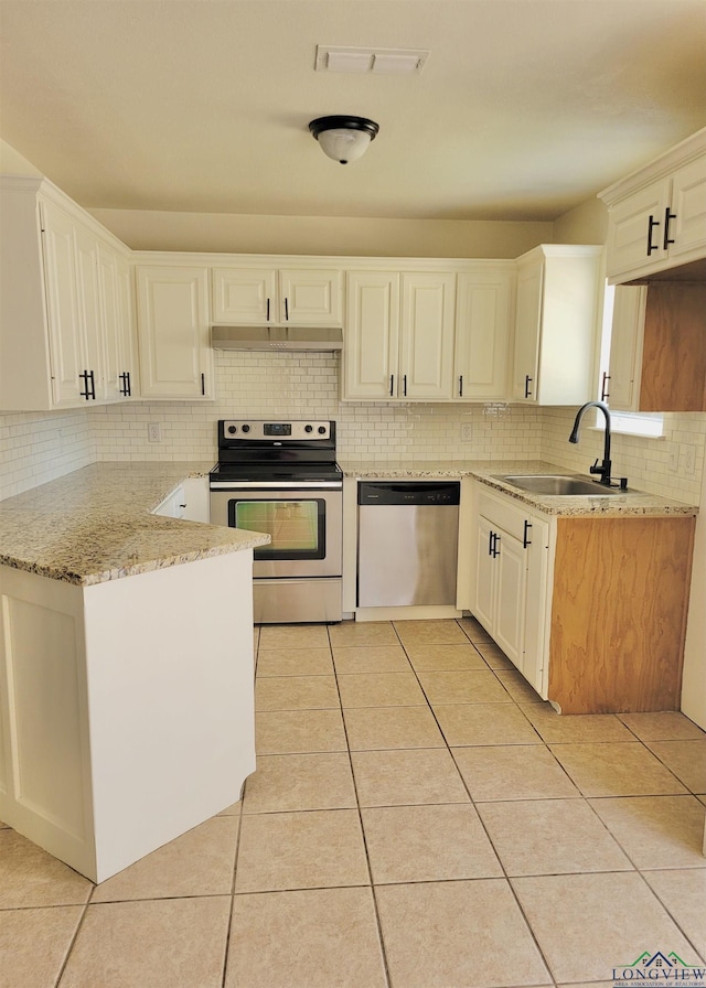 kitchen featuring white cabinets, sink, light stone countertops, light tile patterned floors, and appliances with stainless steel finishes