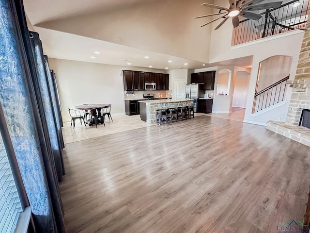 1126 Ruddy Duck, New Braunfels, TX 78130 - living room with ceiling fan, baseboards, light wood-style floors, a towering ceiling, and stairway