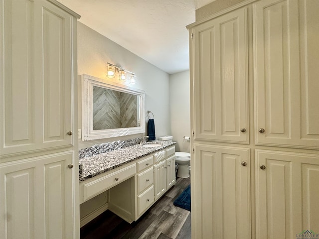 bathroom featuring wood-type flooring, toilet, and vanity