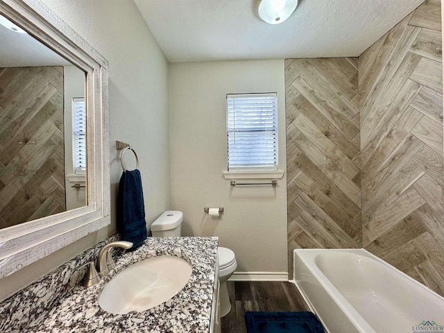 bathroom featuring toilet, hardwood / wood-style floors, a washtub, and vanity