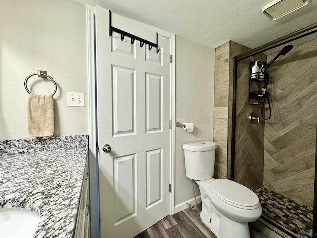 bathroom featuring toilet, tiled shower, wood-type flooring, a textured ceiling, and vanity