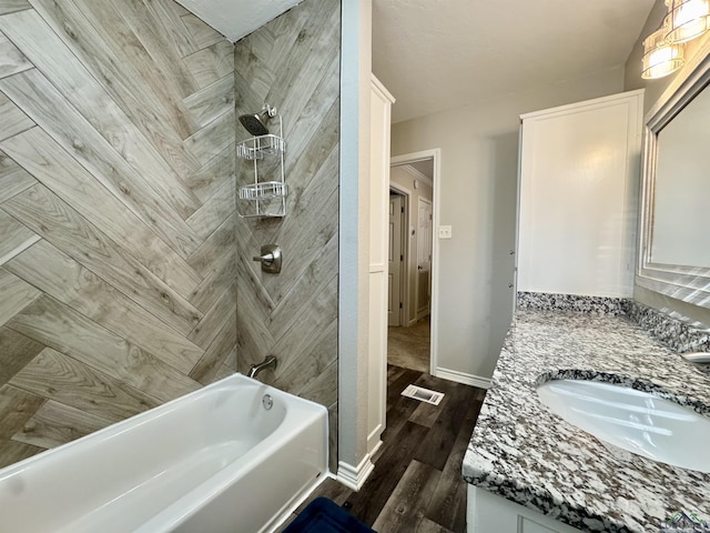 bathroom featuring hardwood / wood-style flooring, tiled shower / bath combo, and vanity