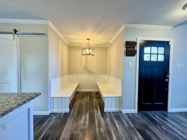 interior space featuring dark hardwood / wood-style flooring, a barn door, a chandelier, and ornamental molding