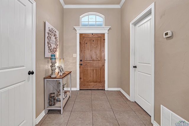 entrance foyer featuring light tile patterned floors, ornamental molding, visible vents, and baseboards