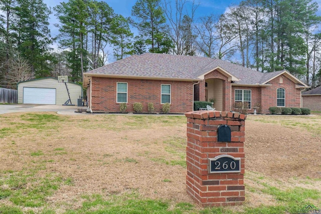 single story home featuring an outbuilding, brick siding, a shingled roof, a front yard, and a garage