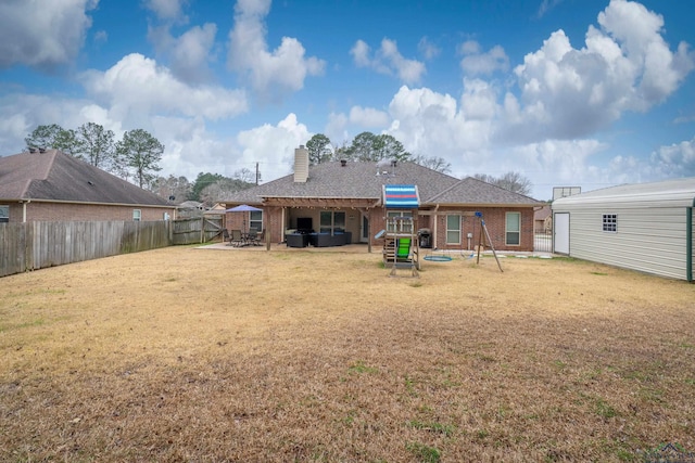 rear view of house with a patio, a fenced backyard, brick siding, a yard, and a chimney