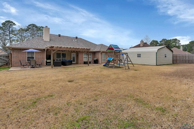 rear view of property with an outbuilding, brick siding, a lawn, a patio area, and fence