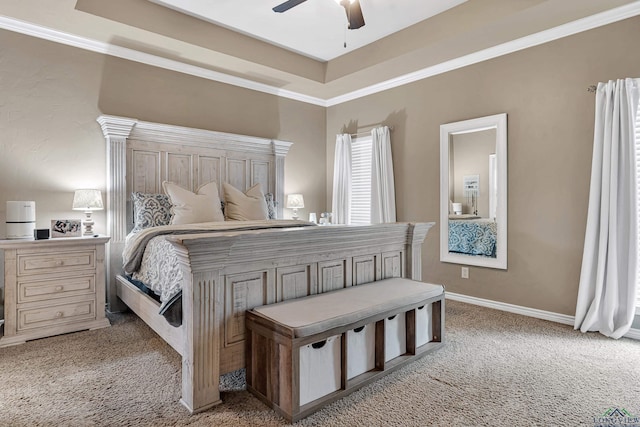 bedroom featuring a ceiling fan, baseboards, ornamental molding, a tray ceiling, and carpet