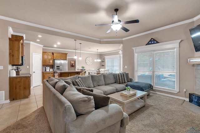 living area with light tile patterned floors, ceiling fan, baseboards, and ornamental molding