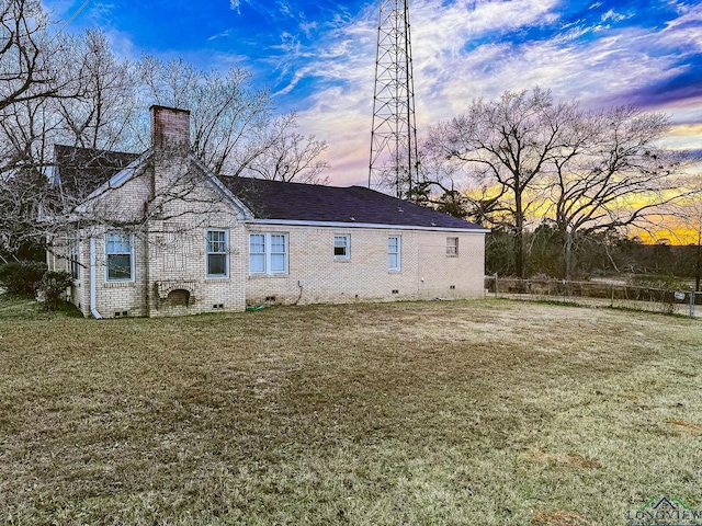 back house at dusk featuring a yard