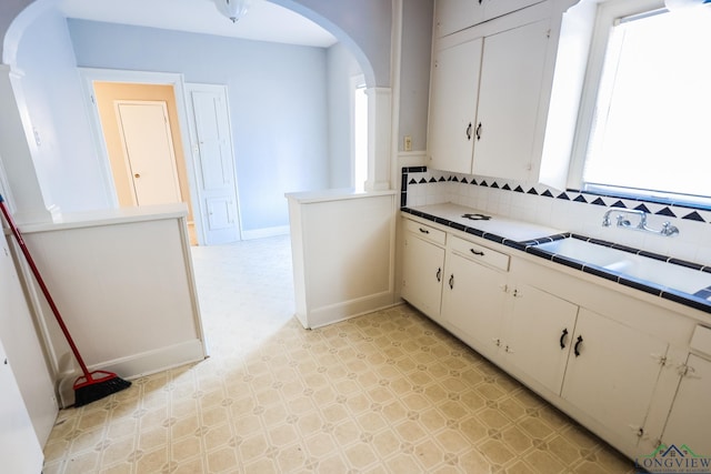 kitchen featuring white cabinetry, tile countertops, sink, and backsplash