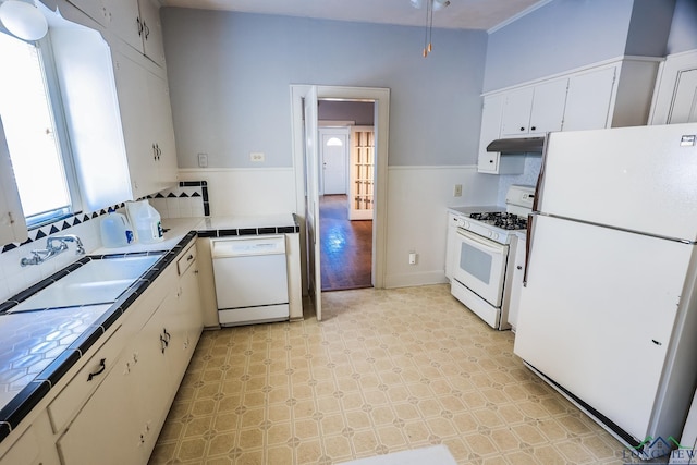 kitchen with sink, tasteful backsplash, tile counters, white appliances, and white cabinets