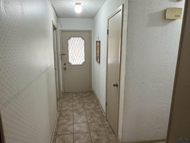 hall with a textured wall, a textured ceiling, and light tile patterned floors