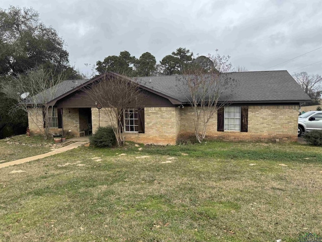 ranch-style house featuring brick siding, roof with shingles, and a front yard