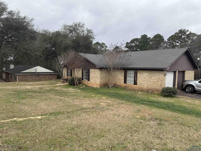 view of front facade with brick siding, a front lawn, an attached garage, and a shingled roof