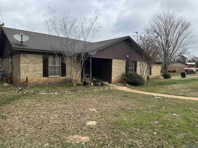 view of front of property featuring roof with shingles, brick siding, and a front lawn