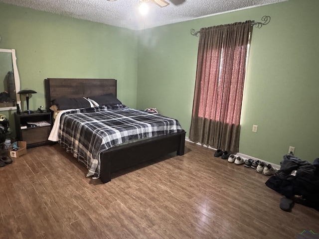 bedroom with a textured ceiling, wood finished floors, and a ceiling fan