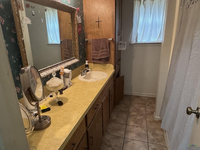 full bath featuring tile patterned flooring, a sink, baseboards, and double vanity