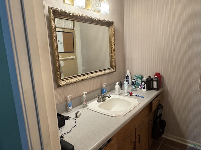 bathroom featuring tile patterned floors, vanity, baseboards, and wallpapered walls